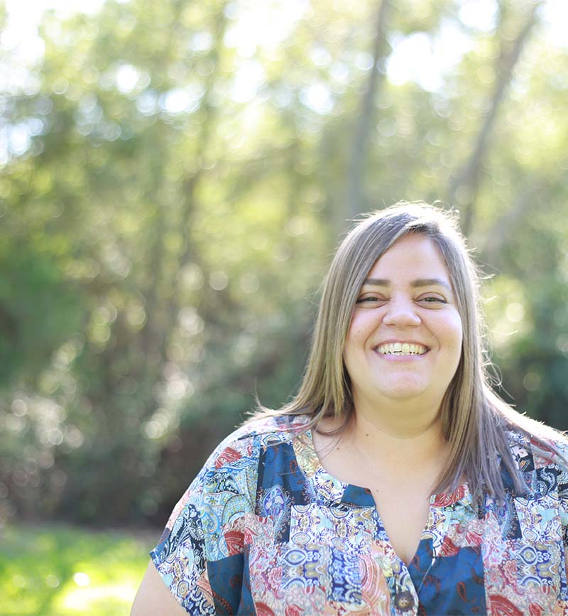 Fotografía de Cristina Castro Martínez. Mujer con un bosque de fondo. Sonríe ampliamente.